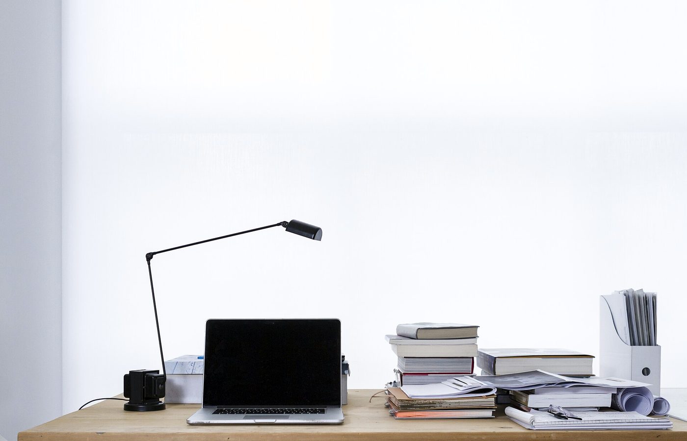 Bureau clair avec une lampe, un ordinateur portable et des piles de livres