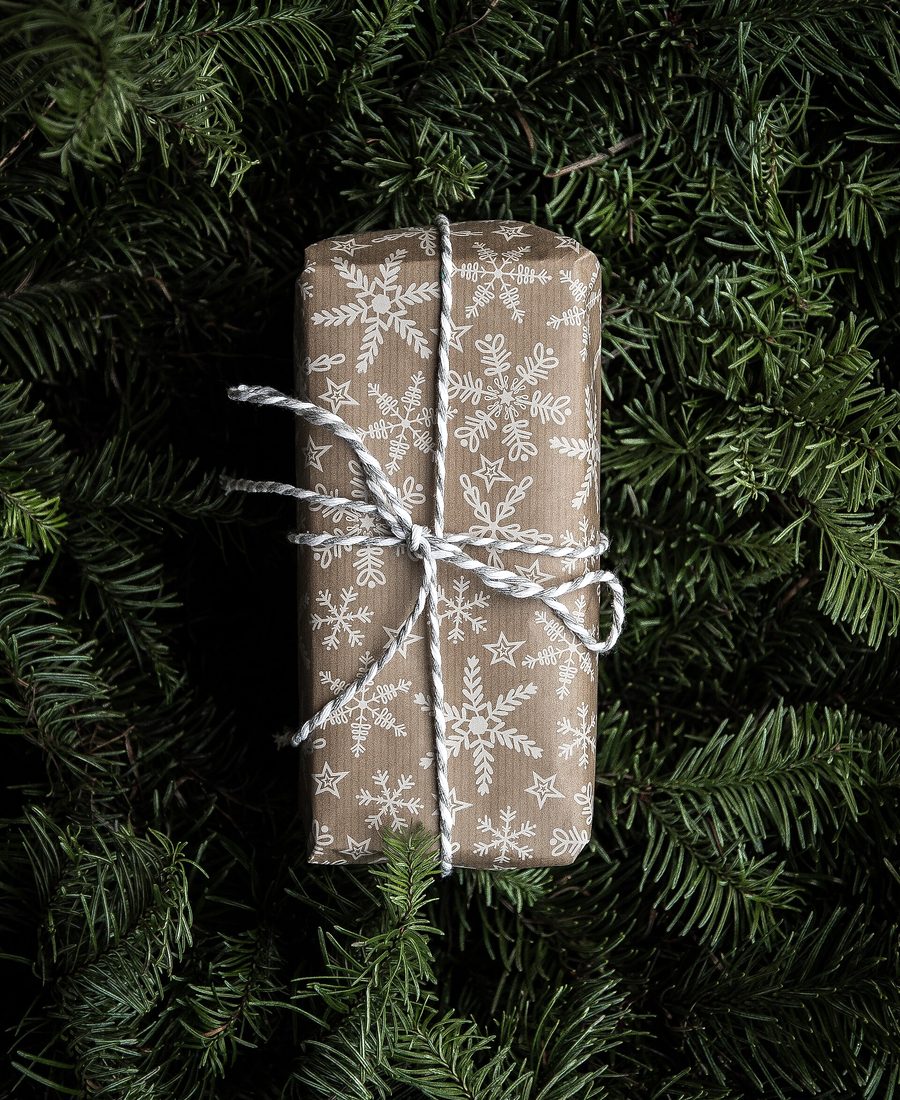 Colis emballé de papier kraft et ficelé, posé sur des branches de sapin